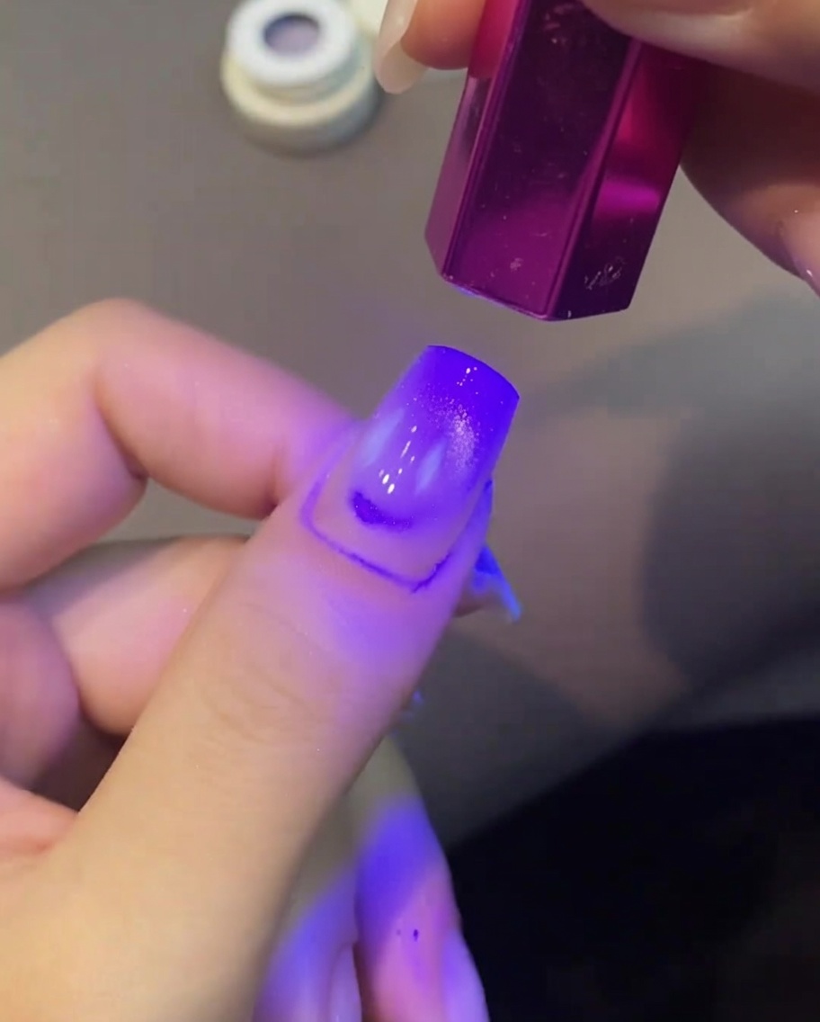 Un ongle vernis cat eye en cours de catalyse sous une petite lampe UV.