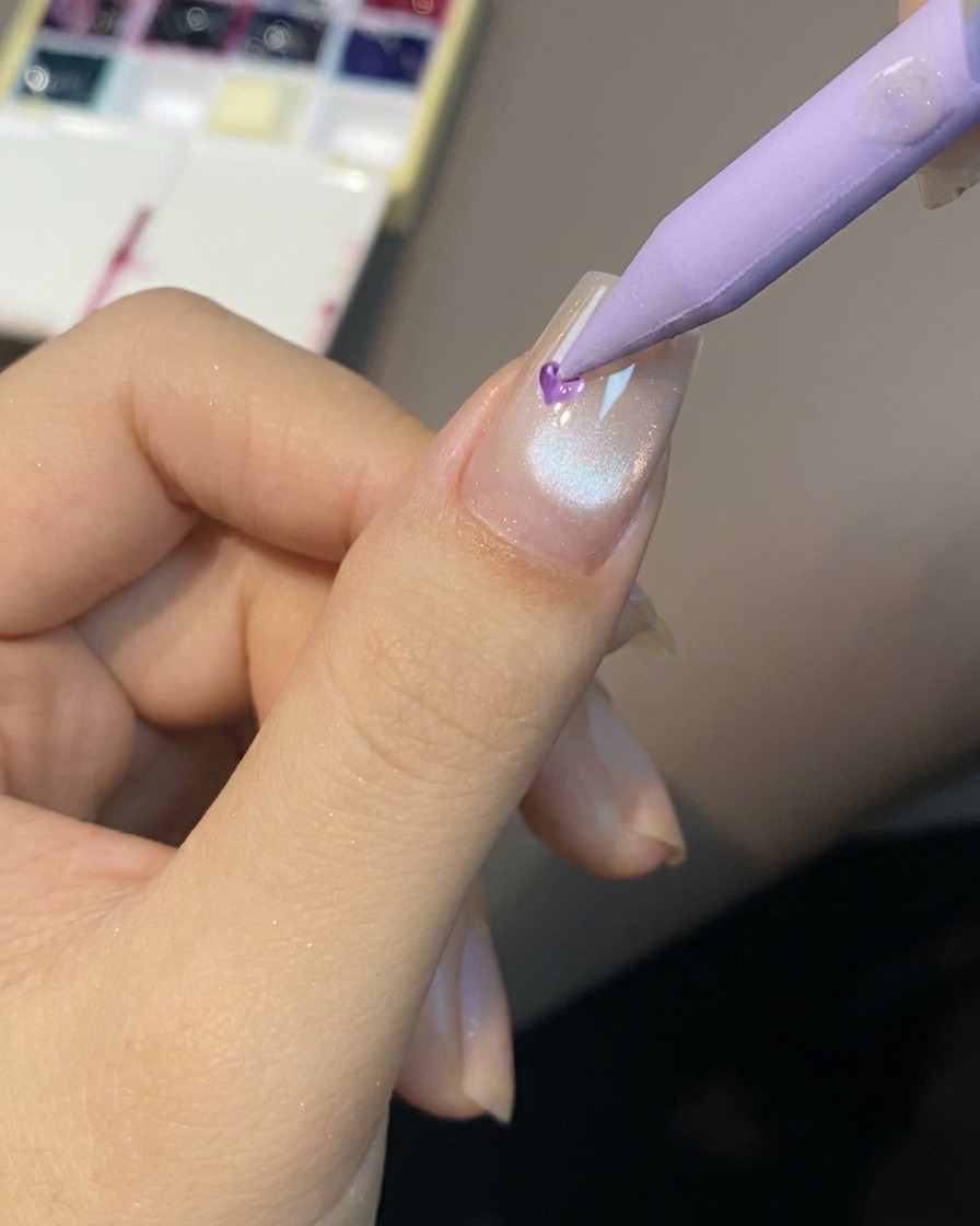 Un outil de précision plaçant une goutte de gel translucide au centre de longle.