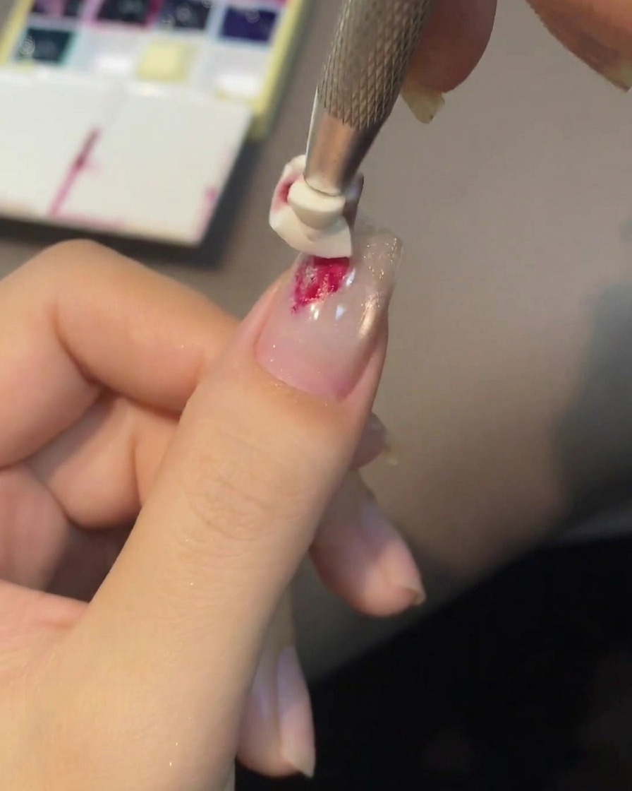 Un outil en silicone pressant une goutte de gel rouge pour créer une rose.