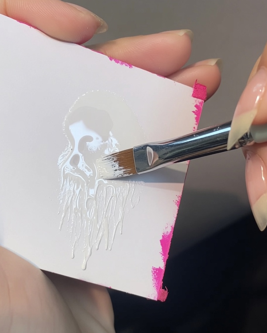 Un pinceau biseauté chargé uniquement sur un coin avec de la peinture gel blanche.