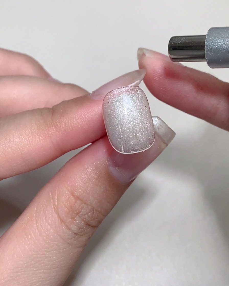 Un aimant utilisé au-dessus dun ongle avec du gel cat-eye humide pour créer un scintillement effet cristal.
