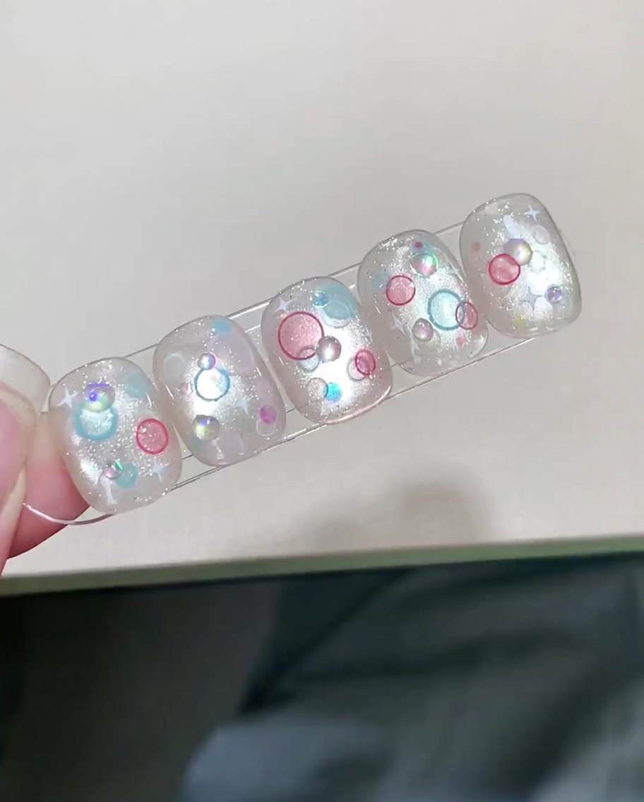 Un ongle fini avec un nail art en bulles 3D en train de catalyser sous une lampe UV/LED.