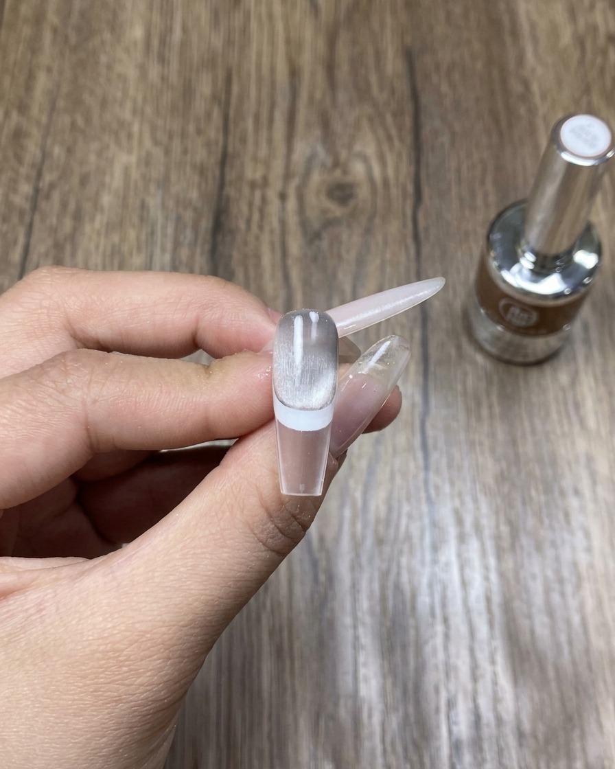 Une main placée dans une lampe UV/LED professionnelle, catalysant le nail art cat eye fraîchement appliqué.
