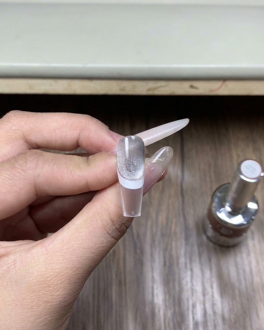 Gros plan sur un petit flacon de top coat spécialisé pour poudre chrome posé sur une surface en bois.
