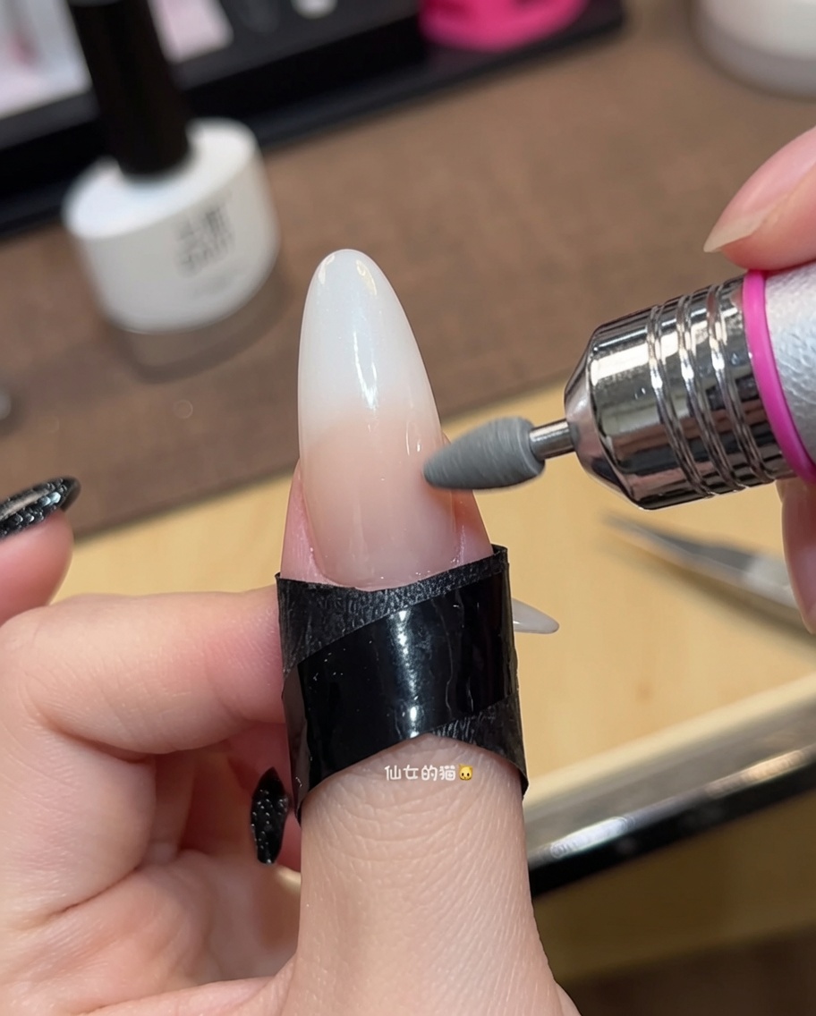 Gros plan dun pinceau appliquant une deuxième couche de vernis gel nude transparent sur un ongle.
