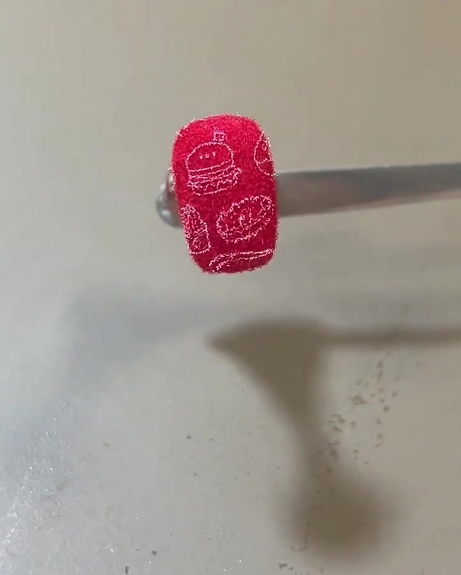 Ongle terminé avec une texture velours rouge orné de motifs food blancs.