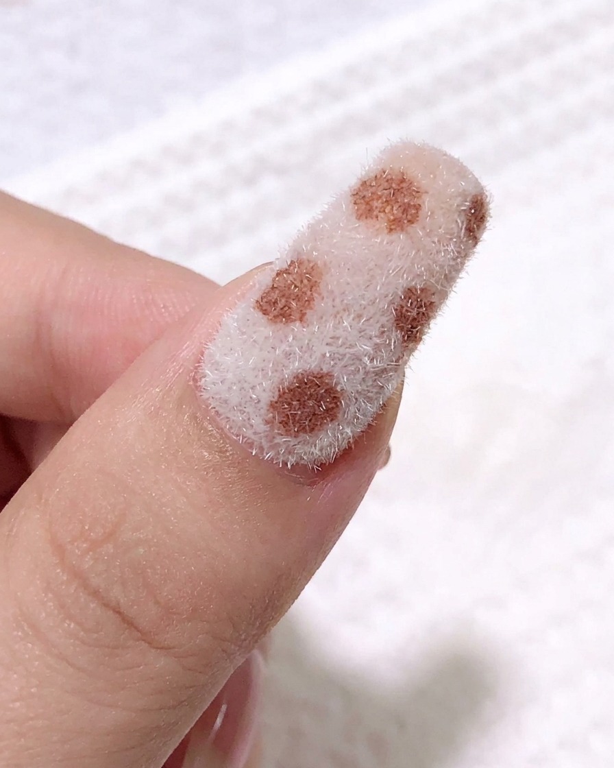 Gros plan montrant un pinceau liner fin appliquant du gel noir pour créer des motifs léopard sur la surface texturée.