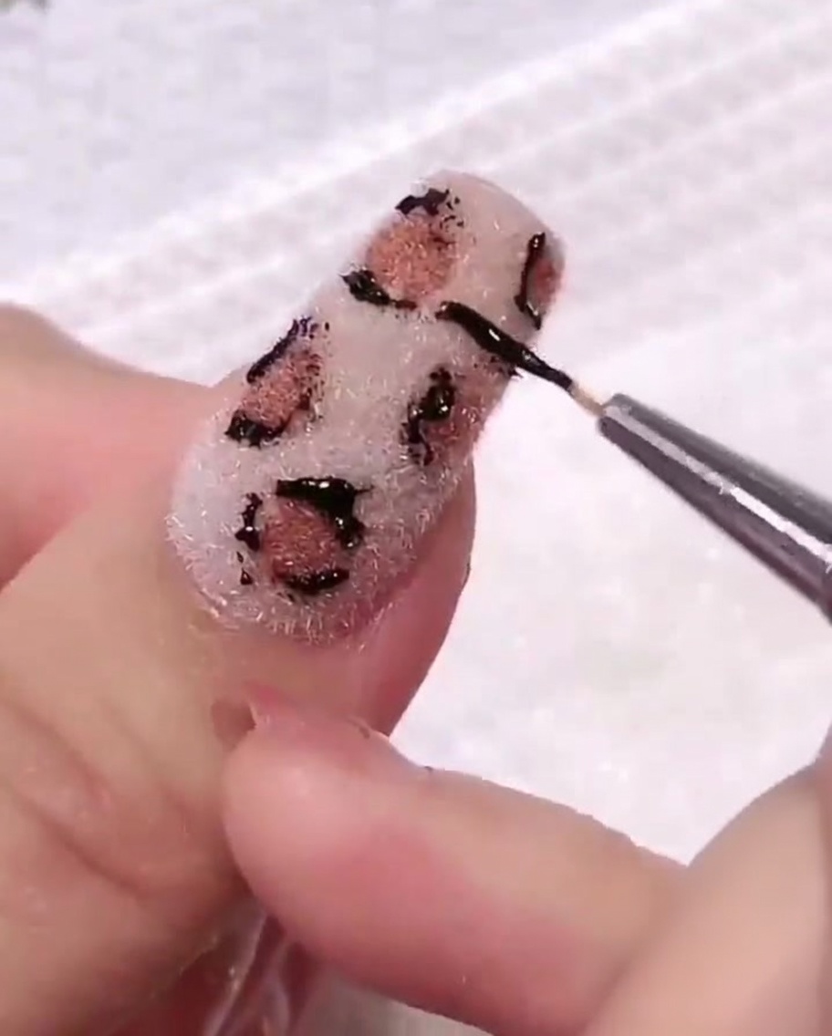 Un coton utilisé pour essuyer délicatement la surface de longle, nettoyant les résidus de gel autour du design.