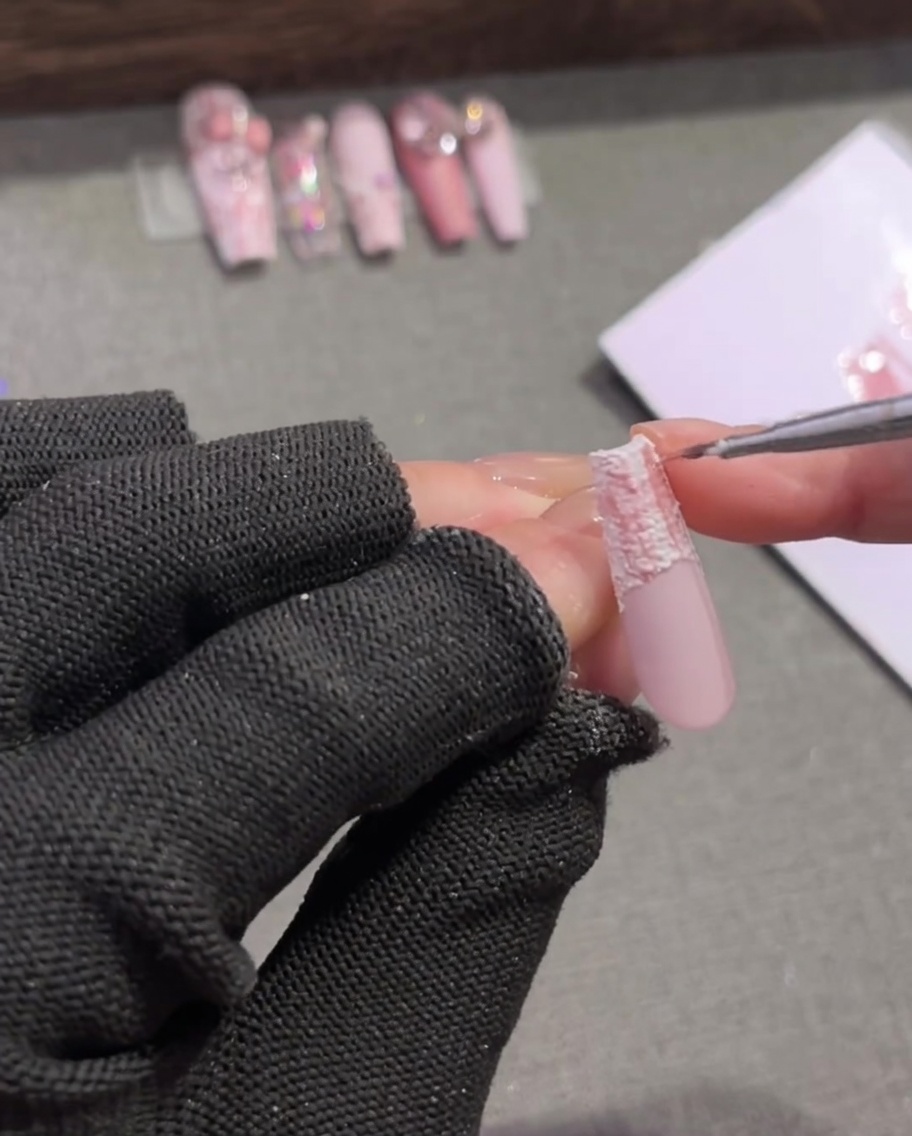 Un pinceau de détail ajoutant de fines lignes marron foncé entrecroisées sur un motif dongle écossais rose et blanc.