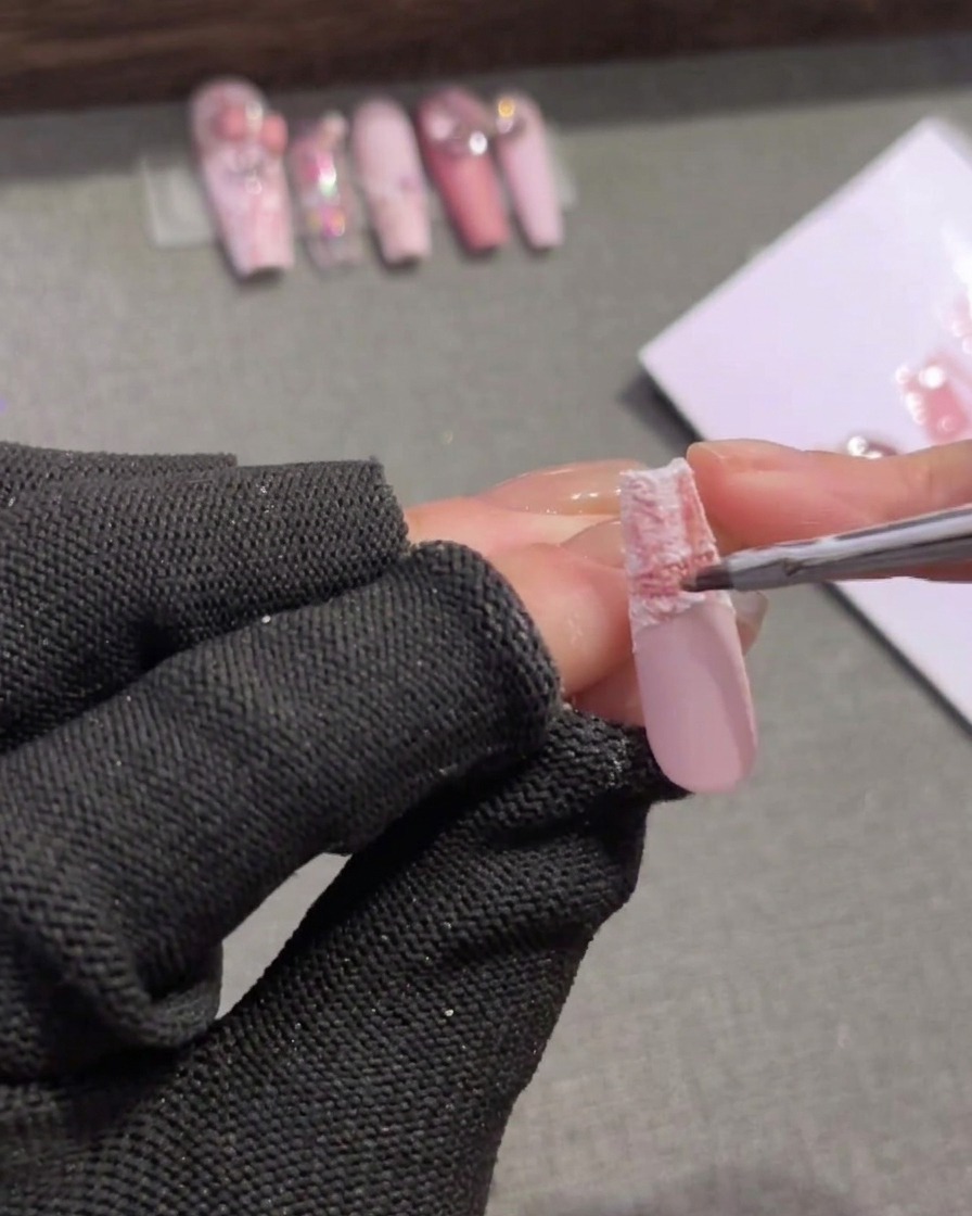 Un pinceau fin appliquant un gel rose de ton moyen sur le bord supérieur dune pointe dongle écossaise pour adoucir la transition.