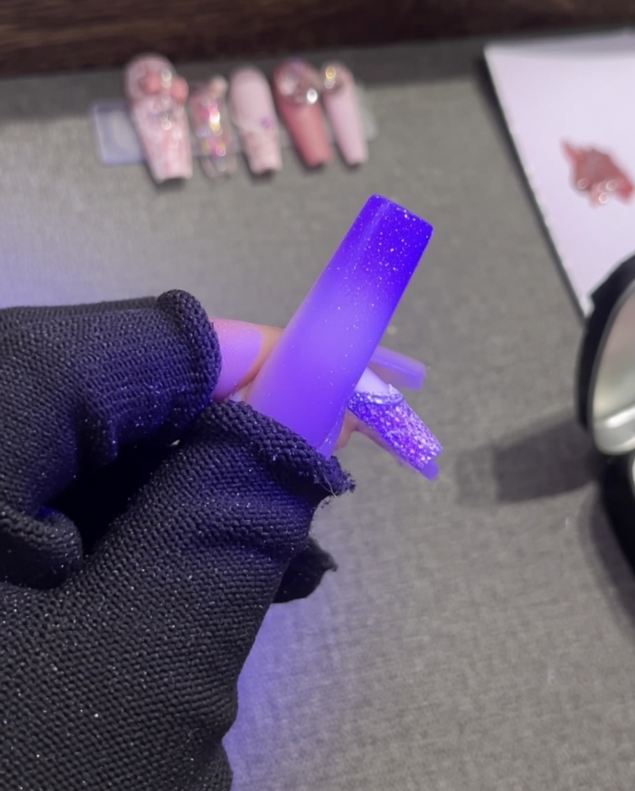 Une pince déposant une petite perle blanche élégante sur le contour en gel plaster blanc humide dune french tip.