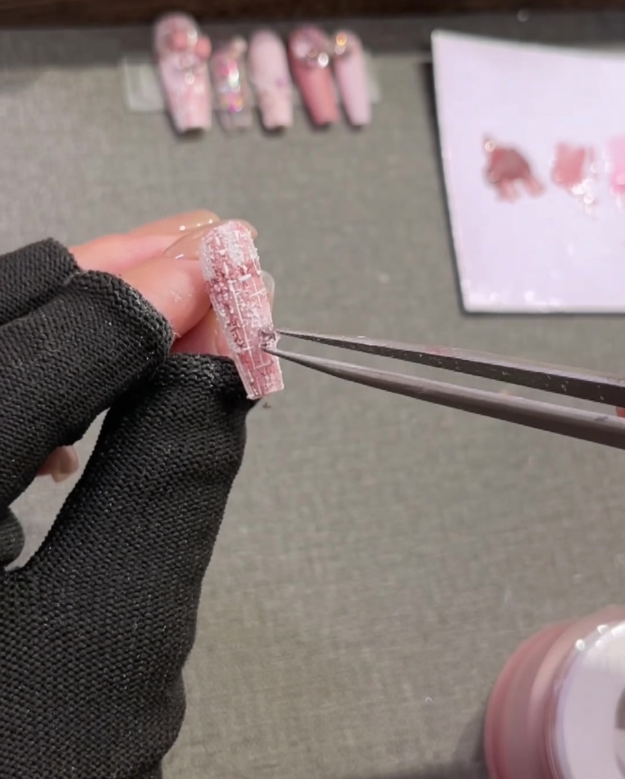 Une paire de pinces plaçant de minuscules strass décoratifs sur une pointe dongle texturée et peinte en écossais.