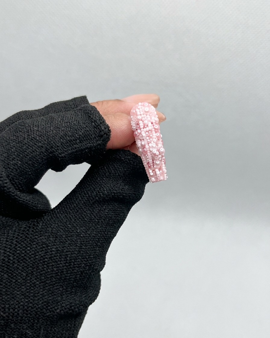 Un pinceau appliquant un gel de base transparent et brillant sur une capsule plastique transparente non peinte.