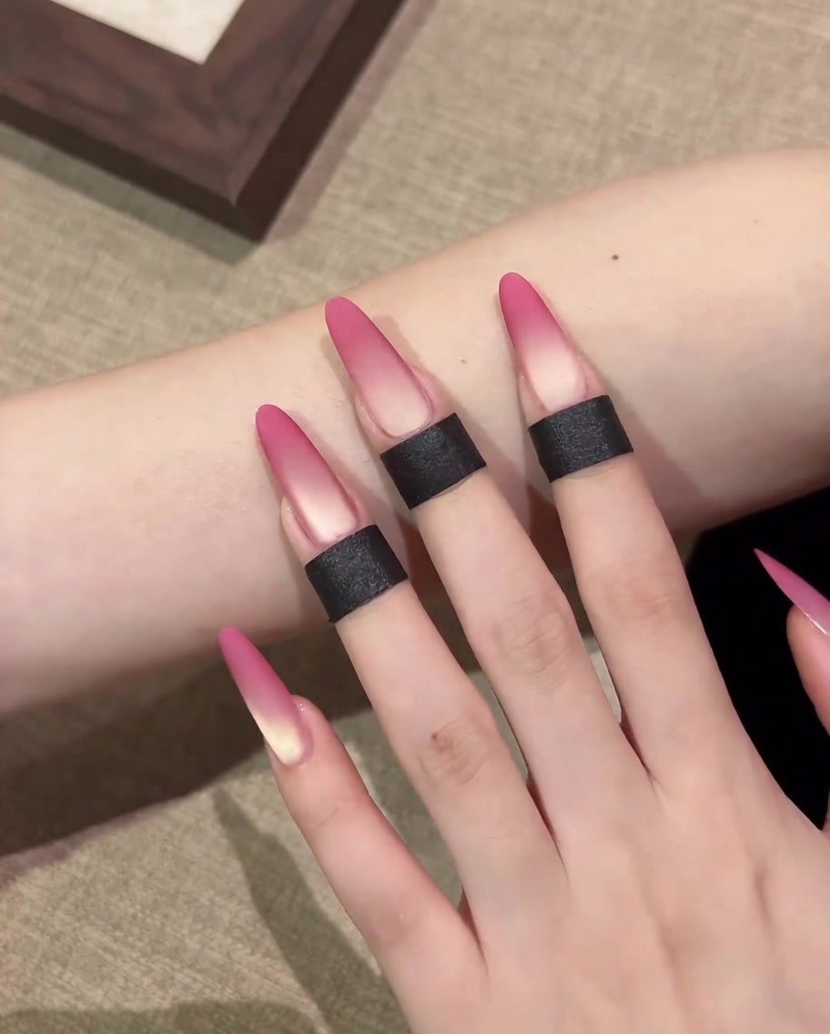 Gros plan montrant une éponge à maquillage appliquant du gel cat-eye rose sur le bout dun ongle.