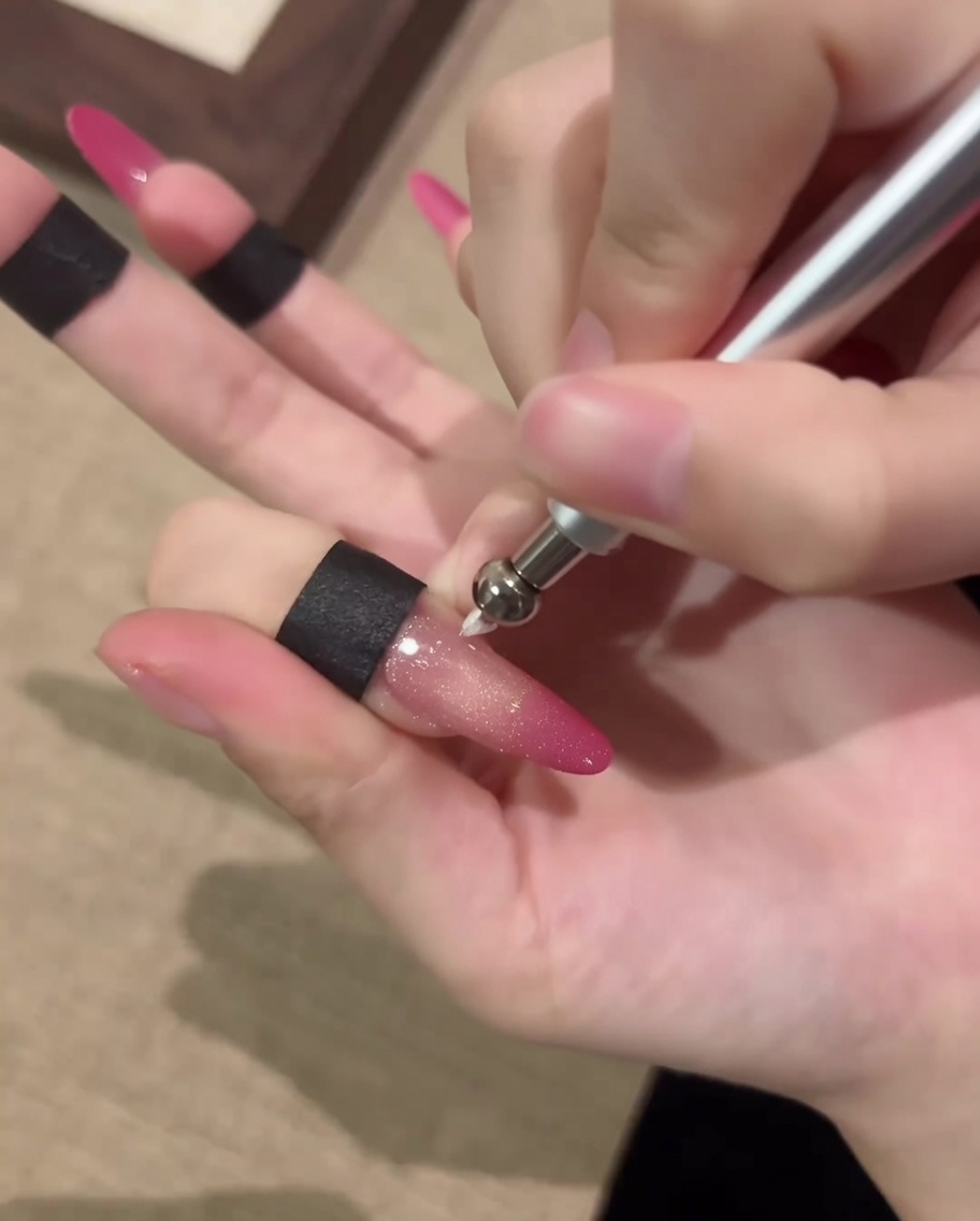 Gros plan dun ongle manipulé avec un stylo magnétique pour former un orbe cat-eye circulaire.
