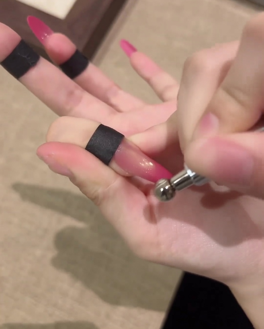 Une main reposant à lintérieur dune lampe à ongles UV professionnelle pour catalyser le design en gel cat-eye terminé.