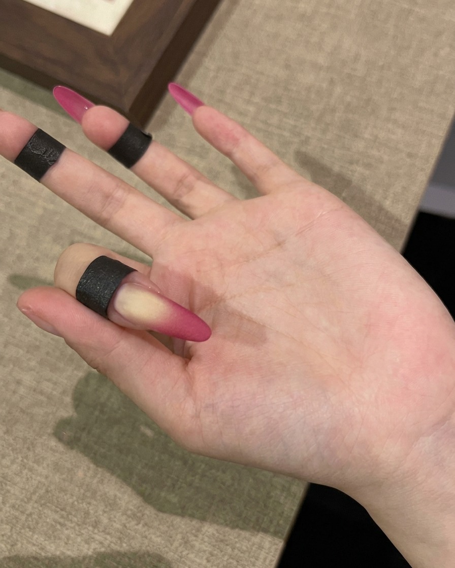 Une main sous une lampe UV pour létape finale de polymérisation du look dongle mat velours.