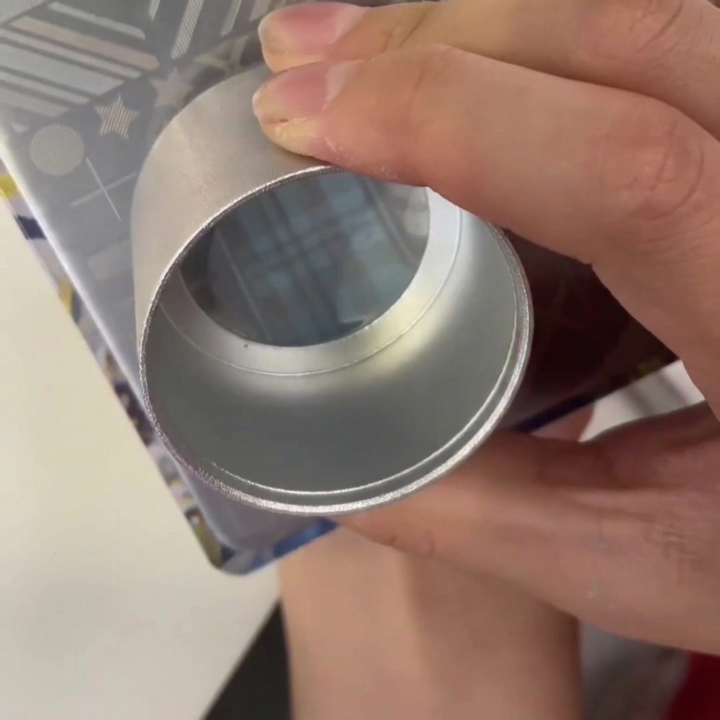 Une raclette en plastique passant sur une plaque métallique contenant du vernis bleu dans le motif gravé.