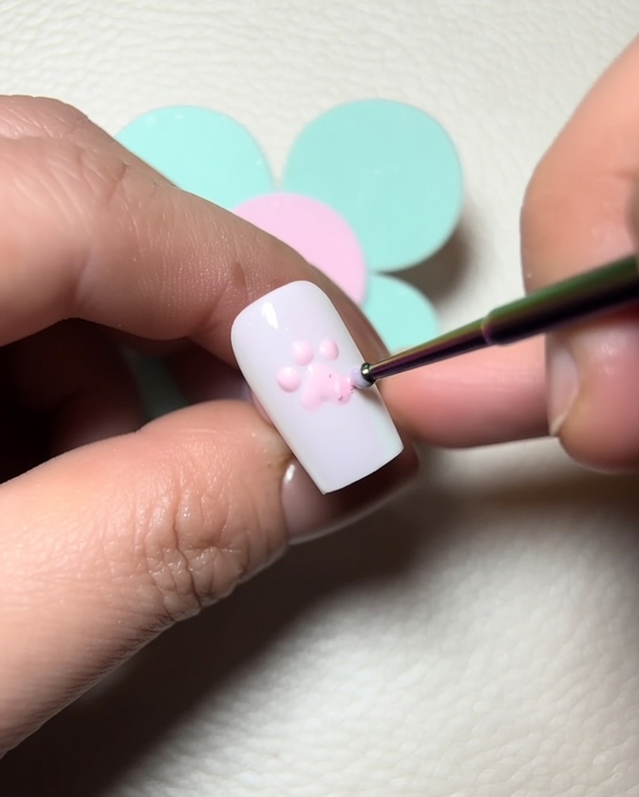 Un pinceau de détail applique du gel de construction transparent sur les points roses pour ajouter du volume.