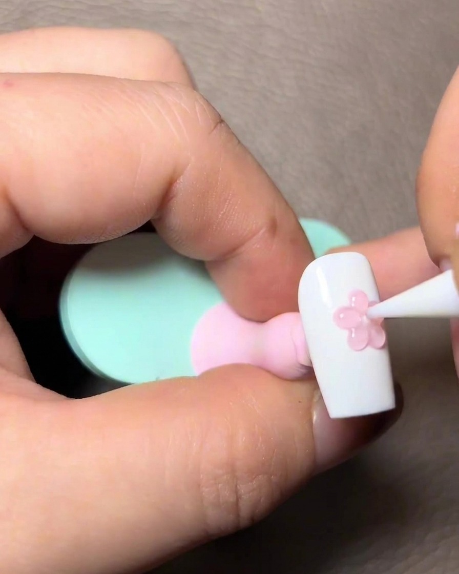 Application dun gel rose transparent sur les détails sculptés en 3D sur longle.
