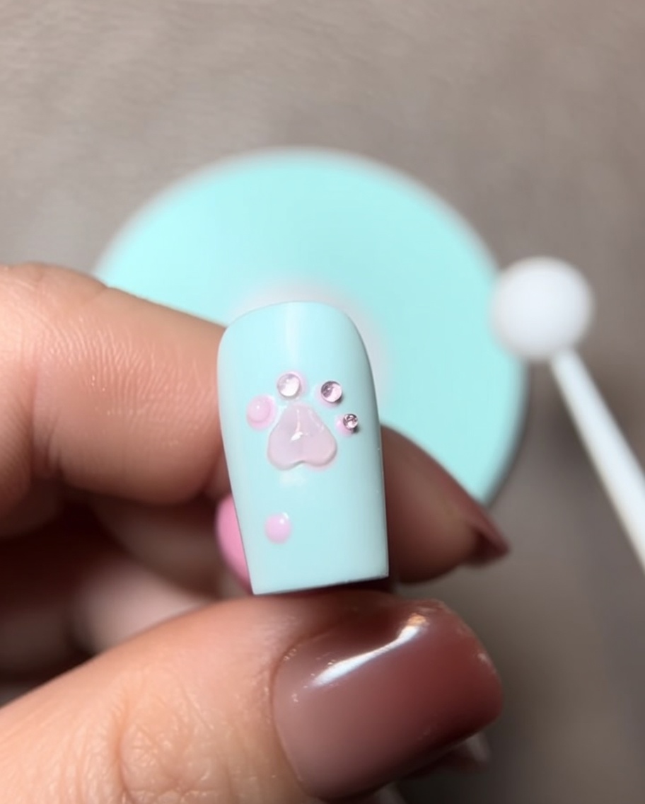 Gros plan dun pinceau ajoutant une perle de gel de construction sur le design de patte 3D.