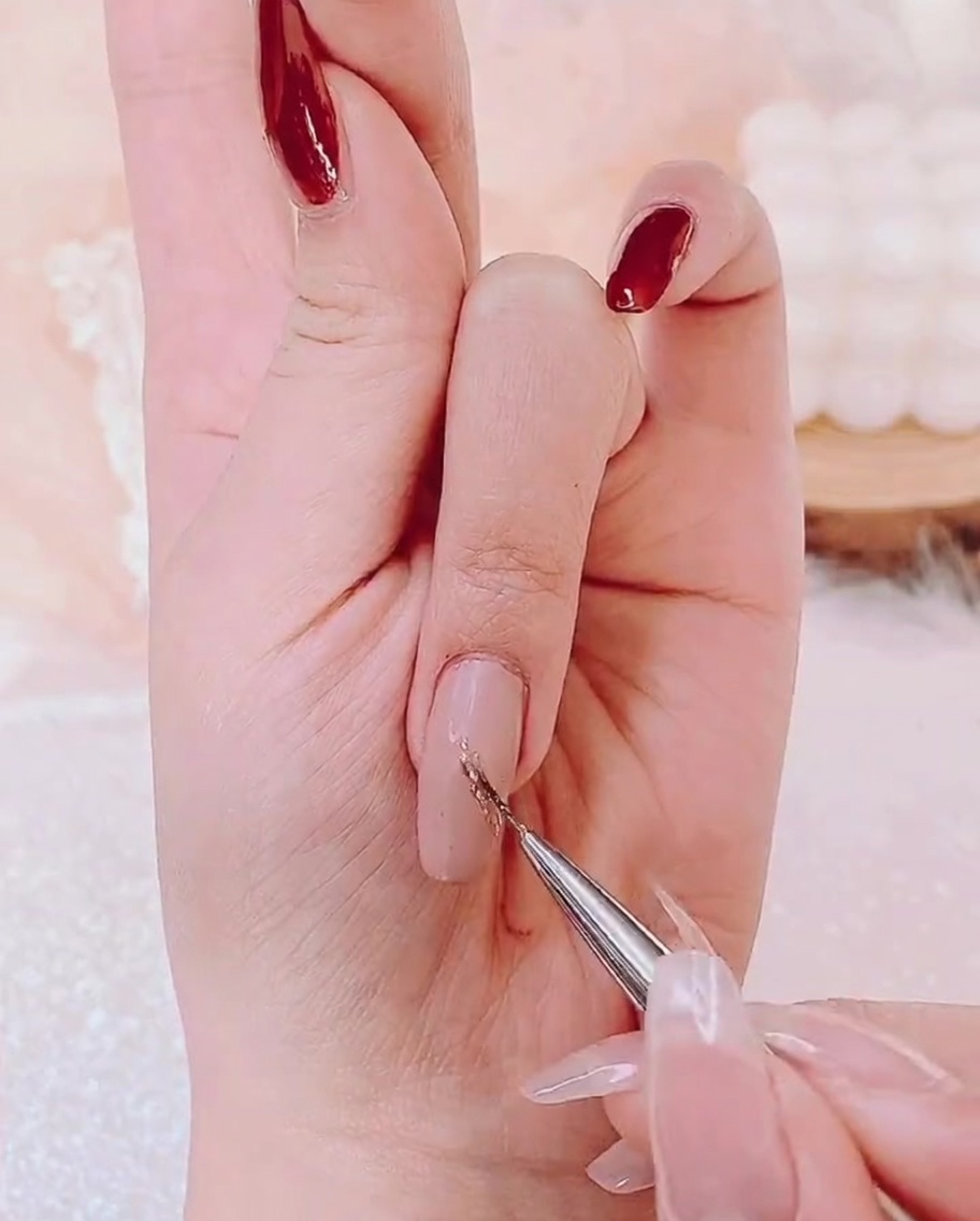 Un pinceau de détail appliquant une fine couche de gel doré scintillant au centre dun ongle.