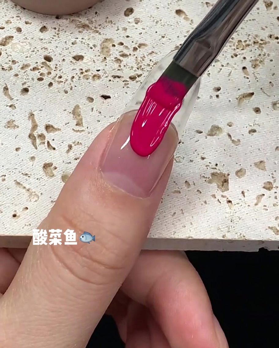 Un coup de pinceau de vernis gel rose vif descendant le long du centre de longle.