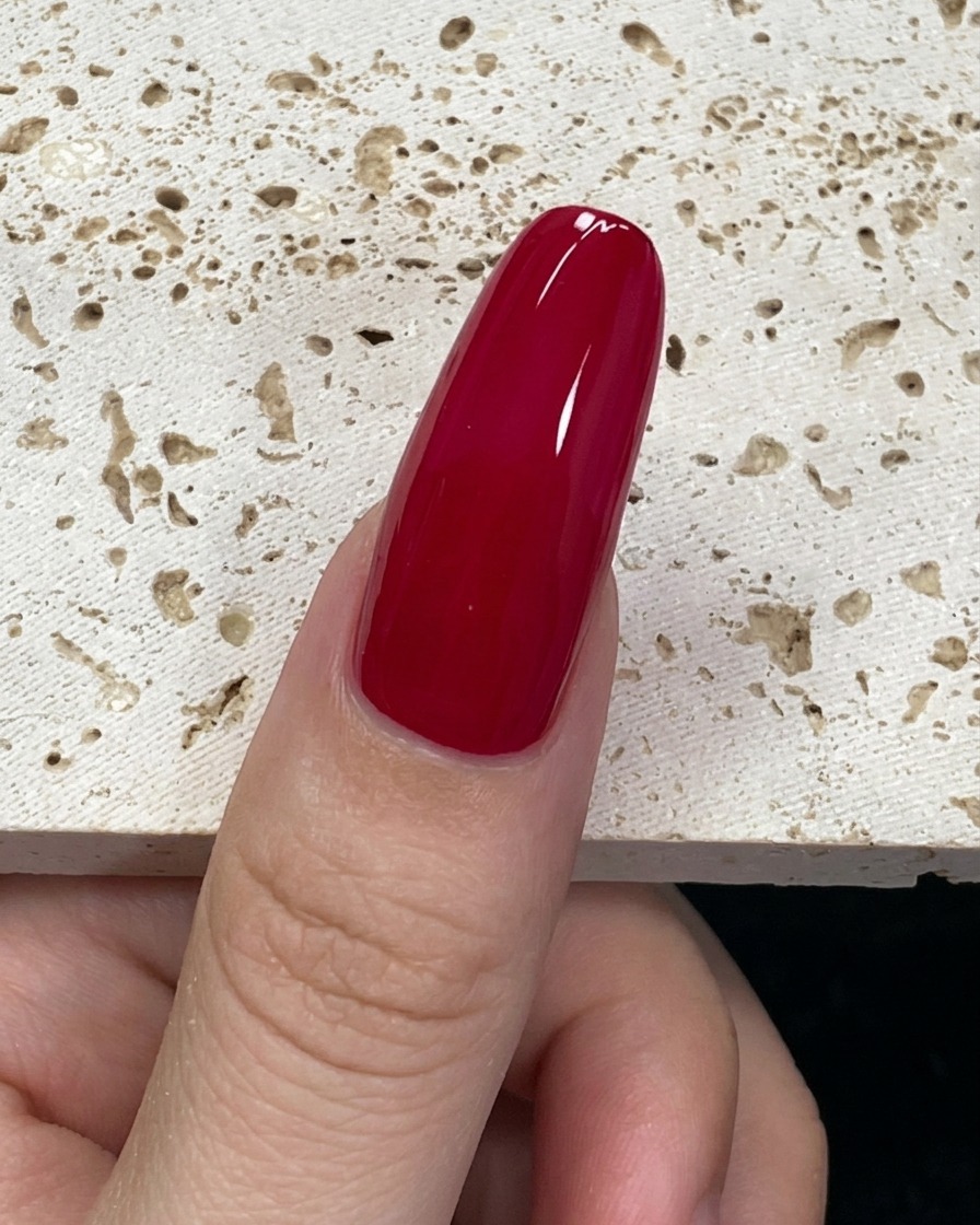 Gros plan sur un pinceau chargé de vernis vert menthe positionné à la base de longle.