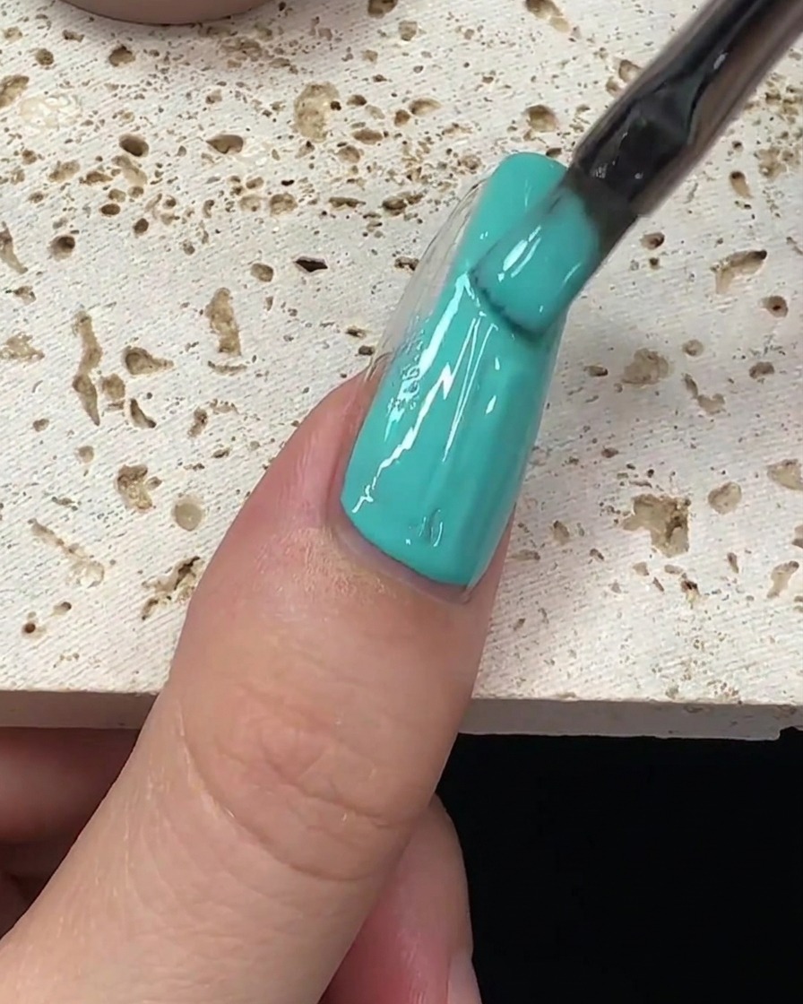 Un trait de vernis vert menthe étiré le long du centre de longle.