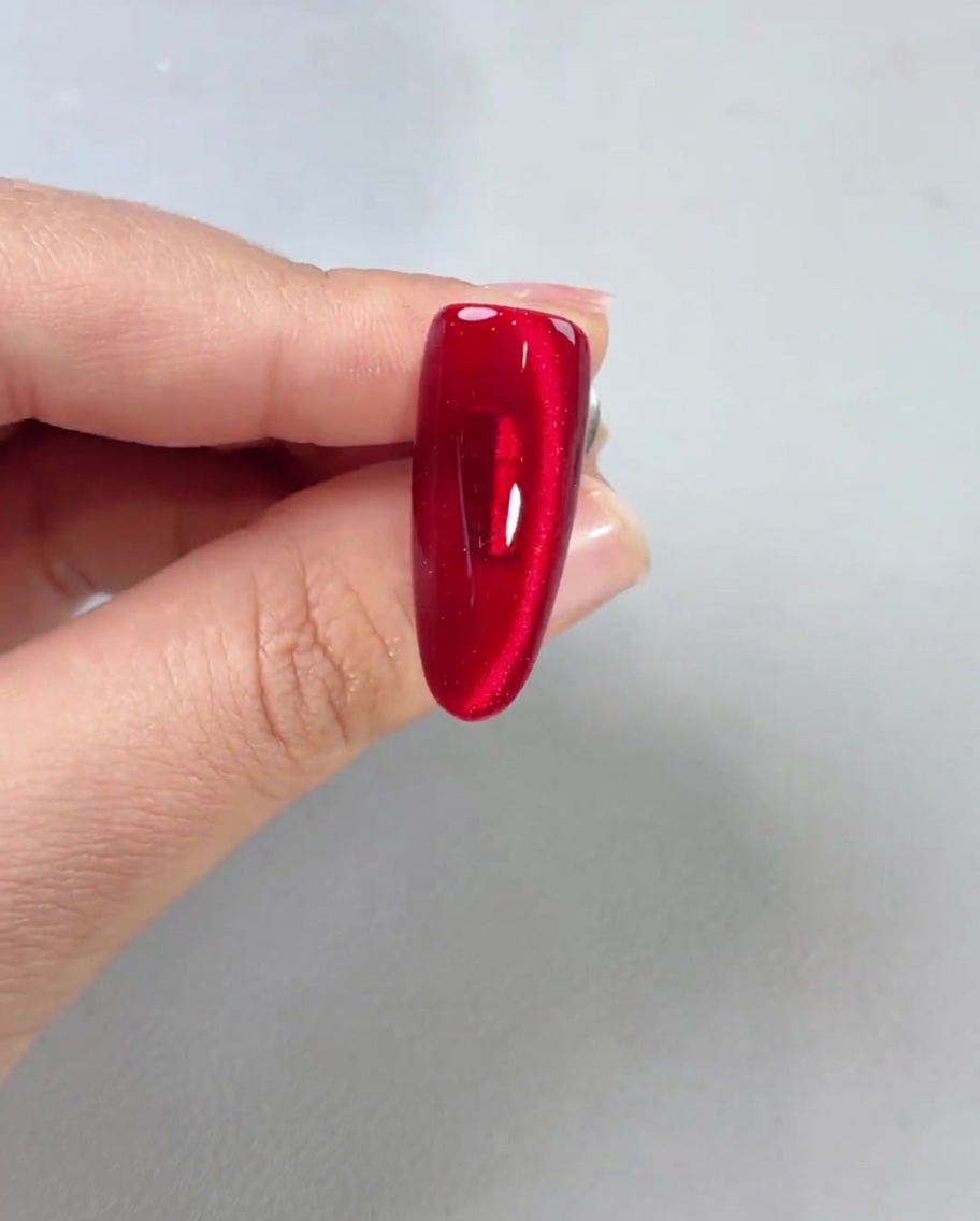 Une couche de finition brillante appliquée sur un ongle magnétique rouge terminé, montrant une grande brillance.