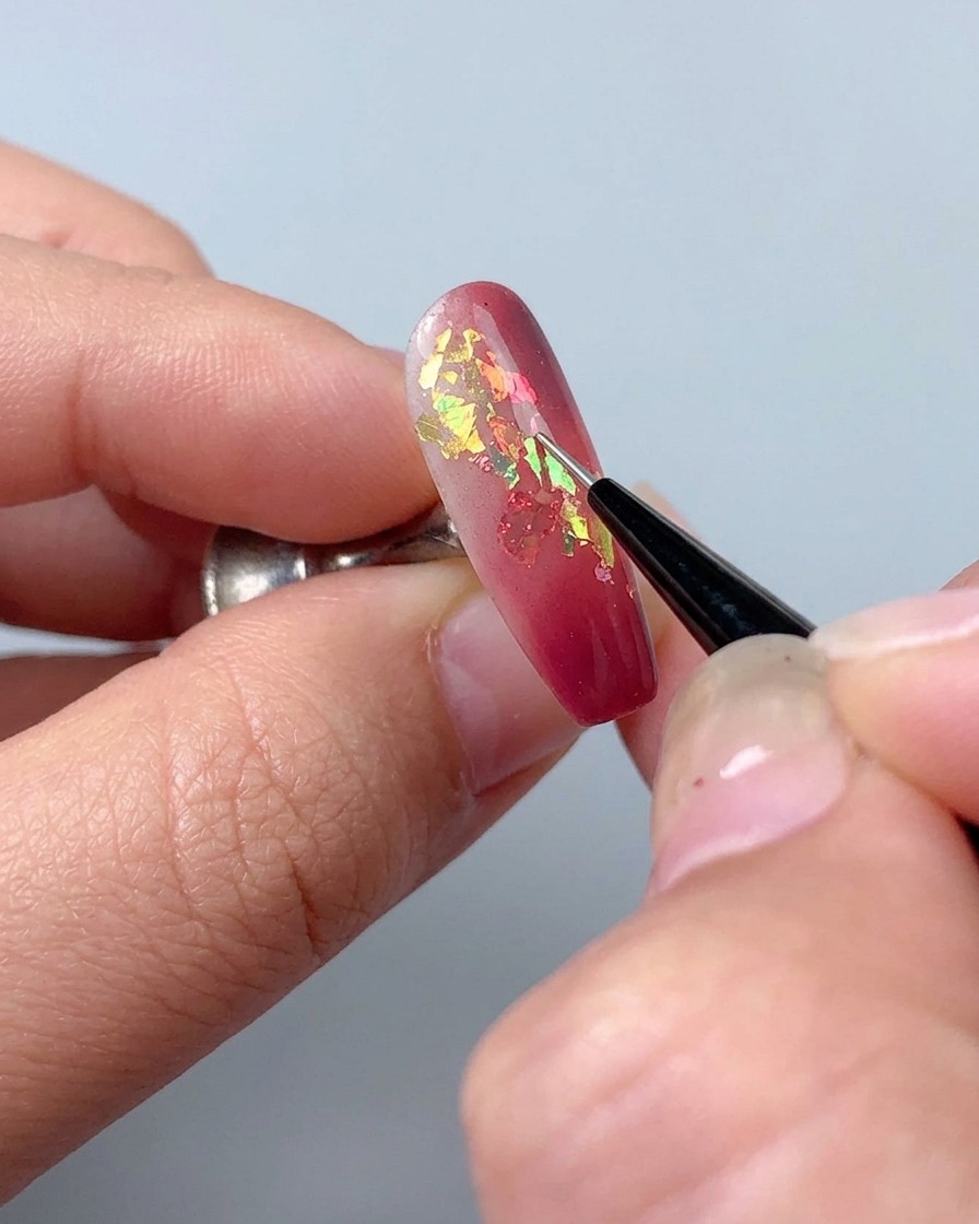 Un pinceau liner utilisé pour dessiner de fines lignes décoratives avec du gel sculptant sur un ongle manucuré.