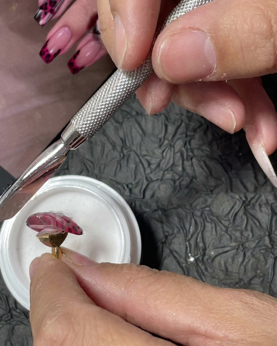 Un outil de manucure utilisé pour saupoudrer de la poudre acrylique fine sur des points de gel rouge humides.