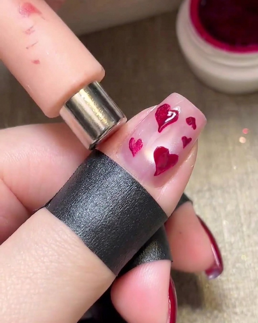 Un aimant maintenu au-dessus de cœurs magenta humides pour créer un effet métallique brillant.