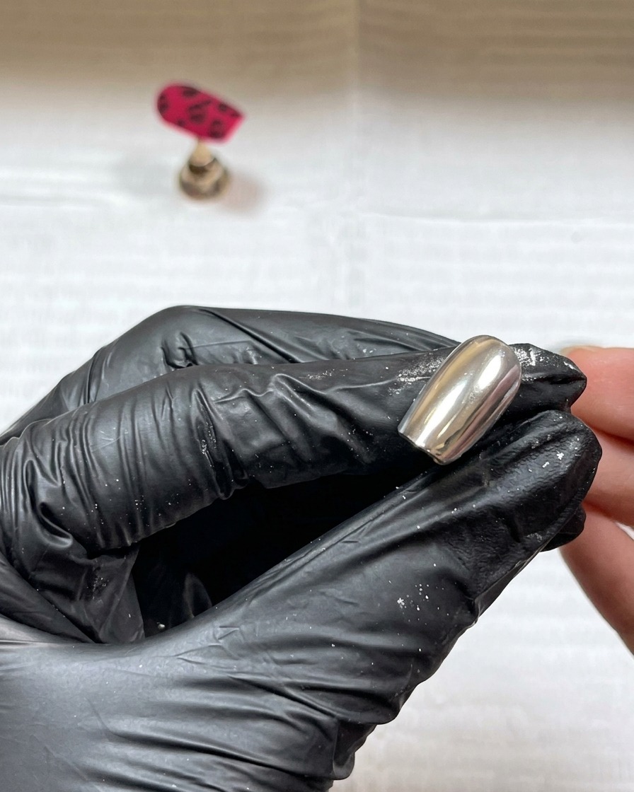 De la poudre acrylique transparente saupoudrée sur les détails de gel noir humides sur longle.