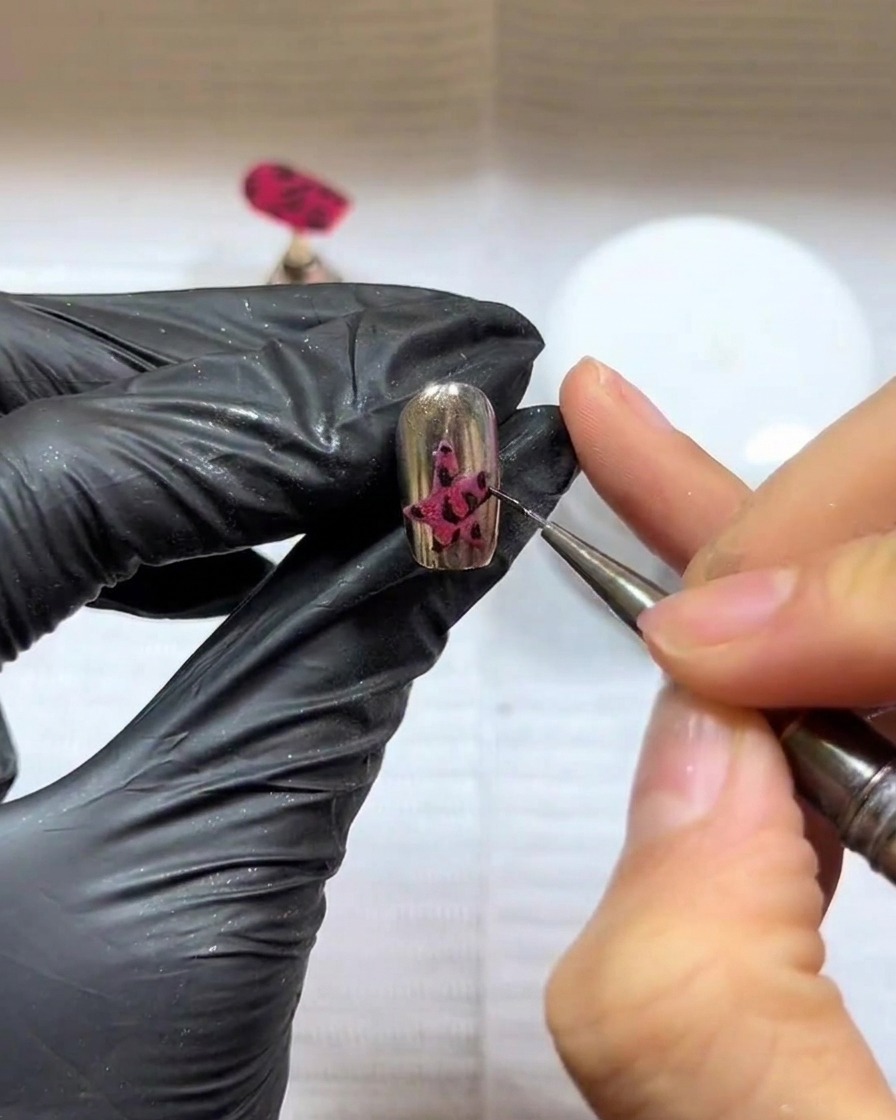 Gros plan dun ongle avec un design détoile sombre, positionné sous une lampe professionnelle UV/LED pour la catalyse.