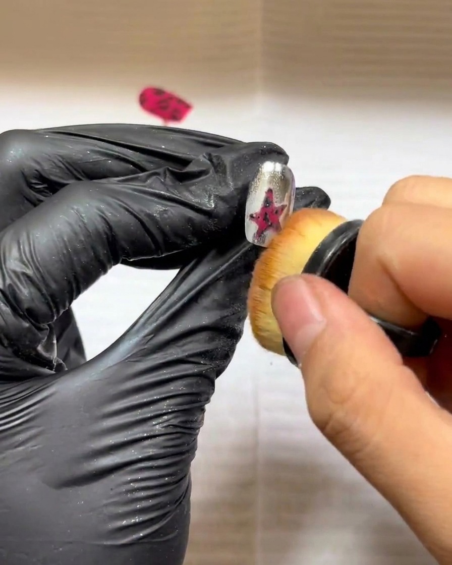 Un petit pinceau de maquillage utilisé pour balayer délicatement lexcédent de poudre dun design dongle en étoile texturé.