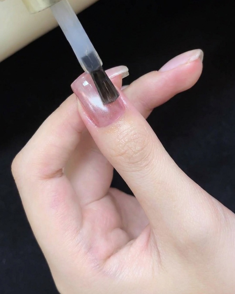 Un pinceau appliquant un top coat brillant sur le design cat eye catalysé.