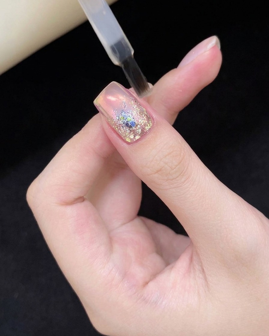Un ongle avec du nail art à paillettes placé dans une lampe UV/LED.