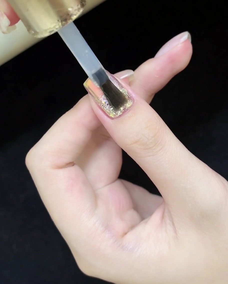 Un pinceau appliquant un top coat brillant sur le design terminé.