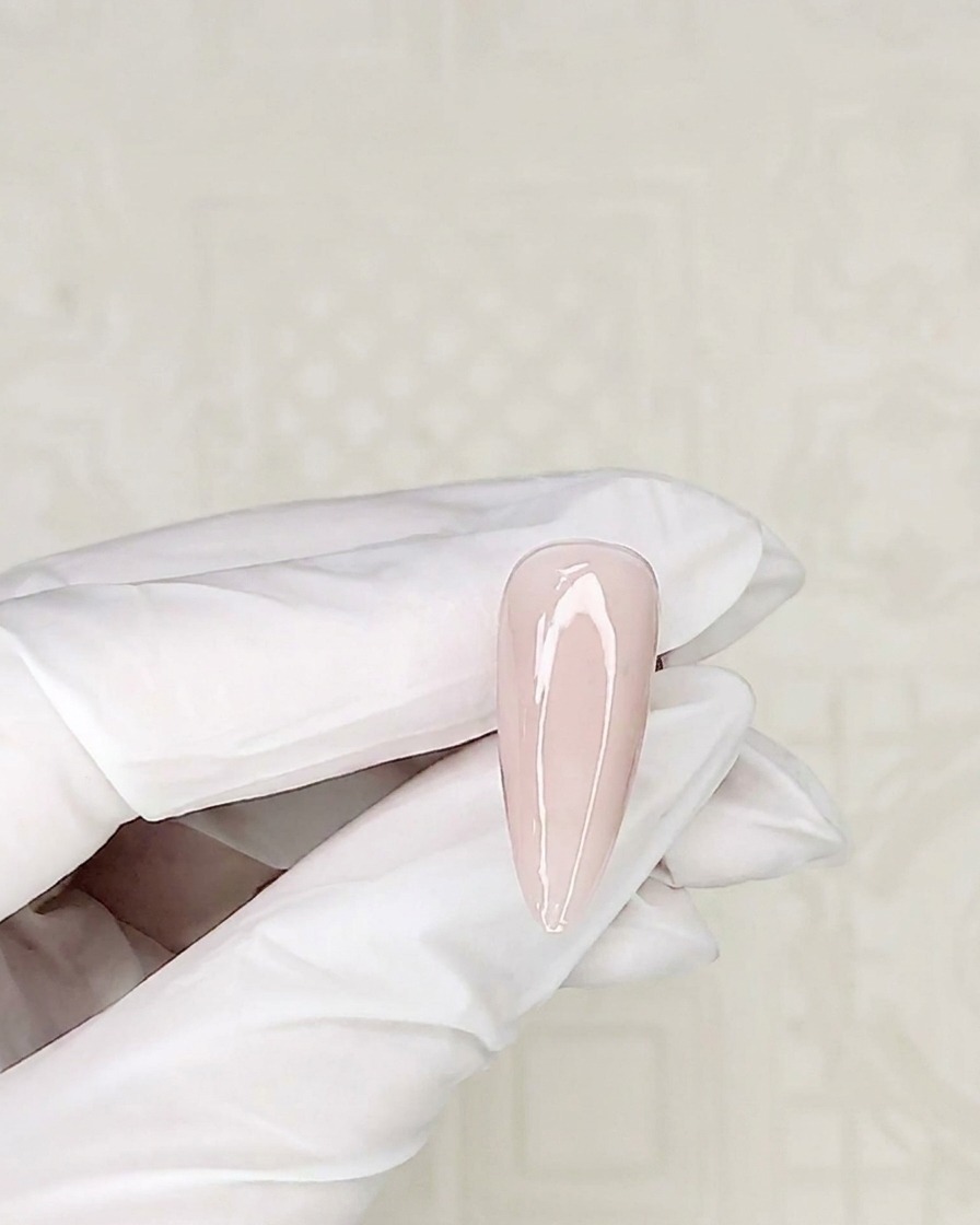 Gros plan sur un pinceau de détail prélevant du vernis gel blanc dans un pot.