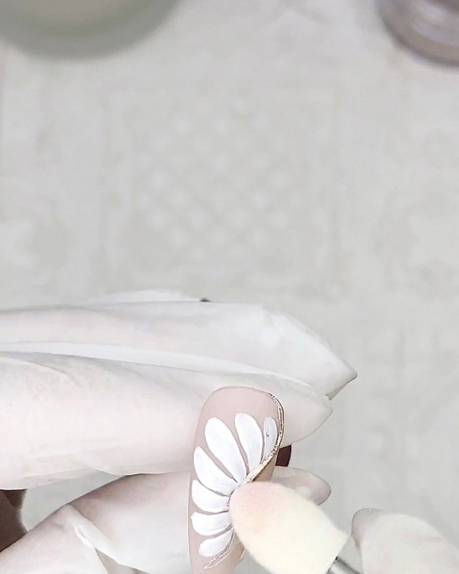 Un embout mousse appliquant de la poudre chromée argentée sur les contours des pétales en adhésif catalysé sur un ongle.