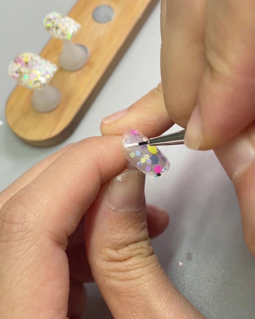 Un pinceau de précision applique du gel de modelage blanc pour former un pétale sur un ongle.