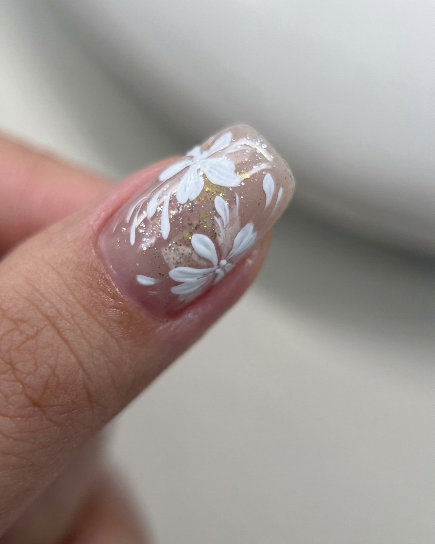 Gros plan dun pinceau liner ajoutant de petits pétales blancs sur un motif floral existant.