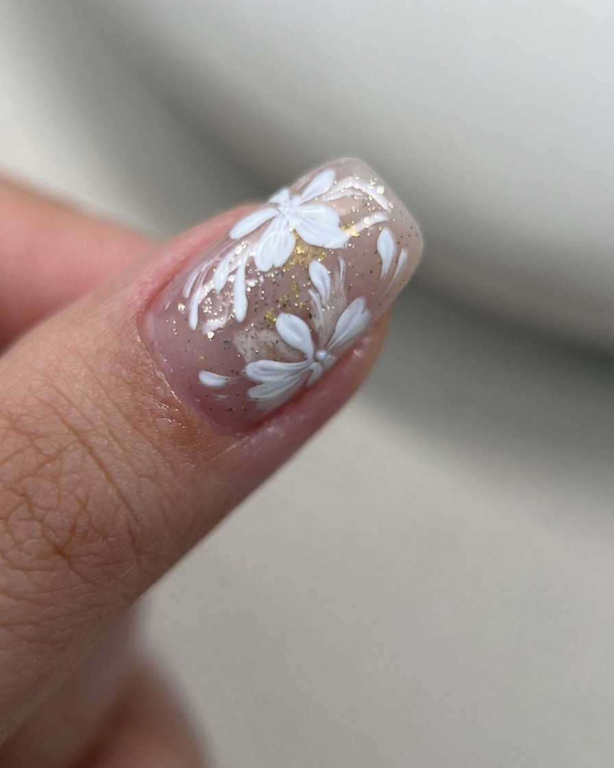 Macro de pétales de fleurs en gel blanc peints en un groupe serré sur un ongle nude.