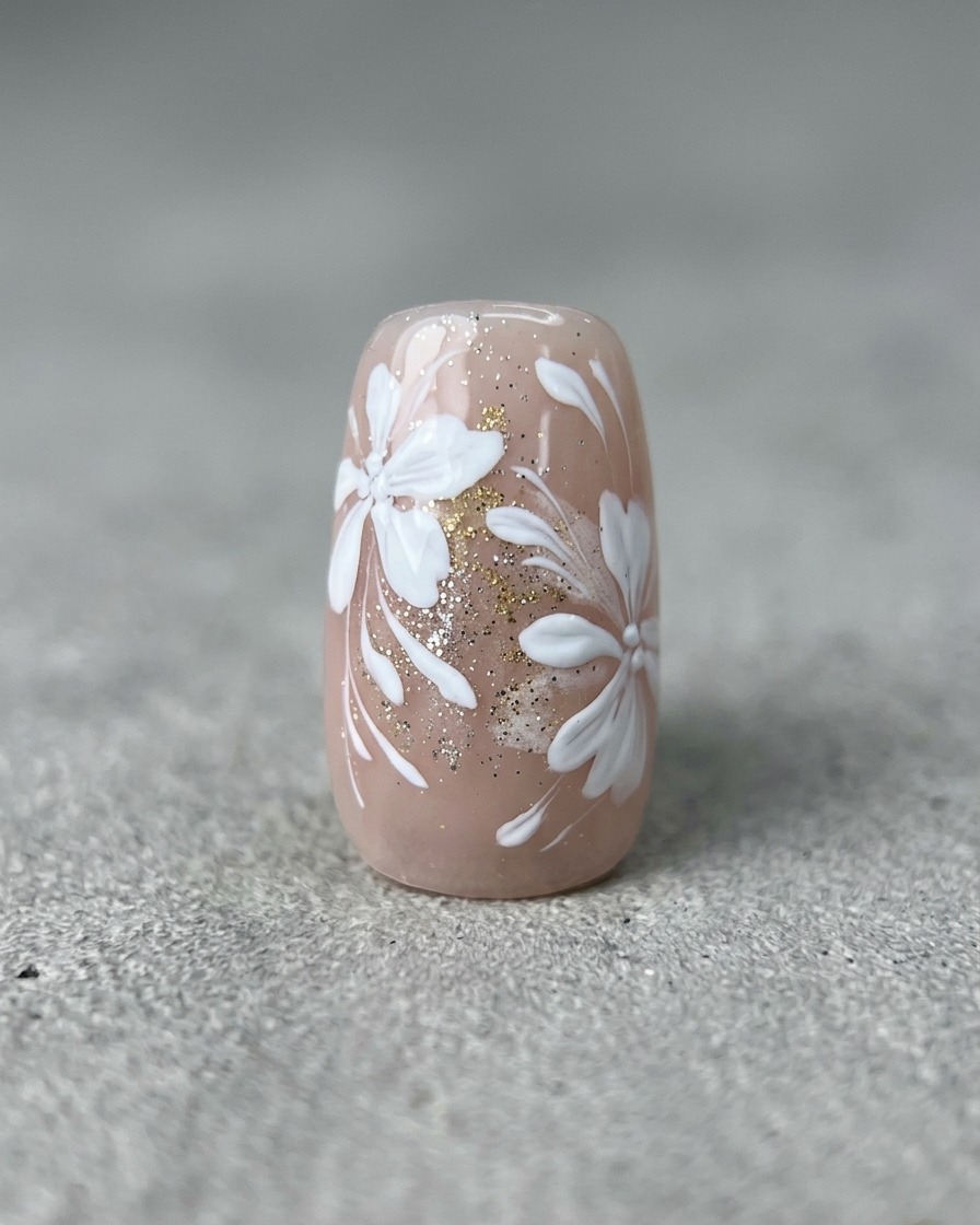 Un pinceau liner fin dessinant de fines lignes blanches incurvées sur un ongle avec un motif floral et doré.
