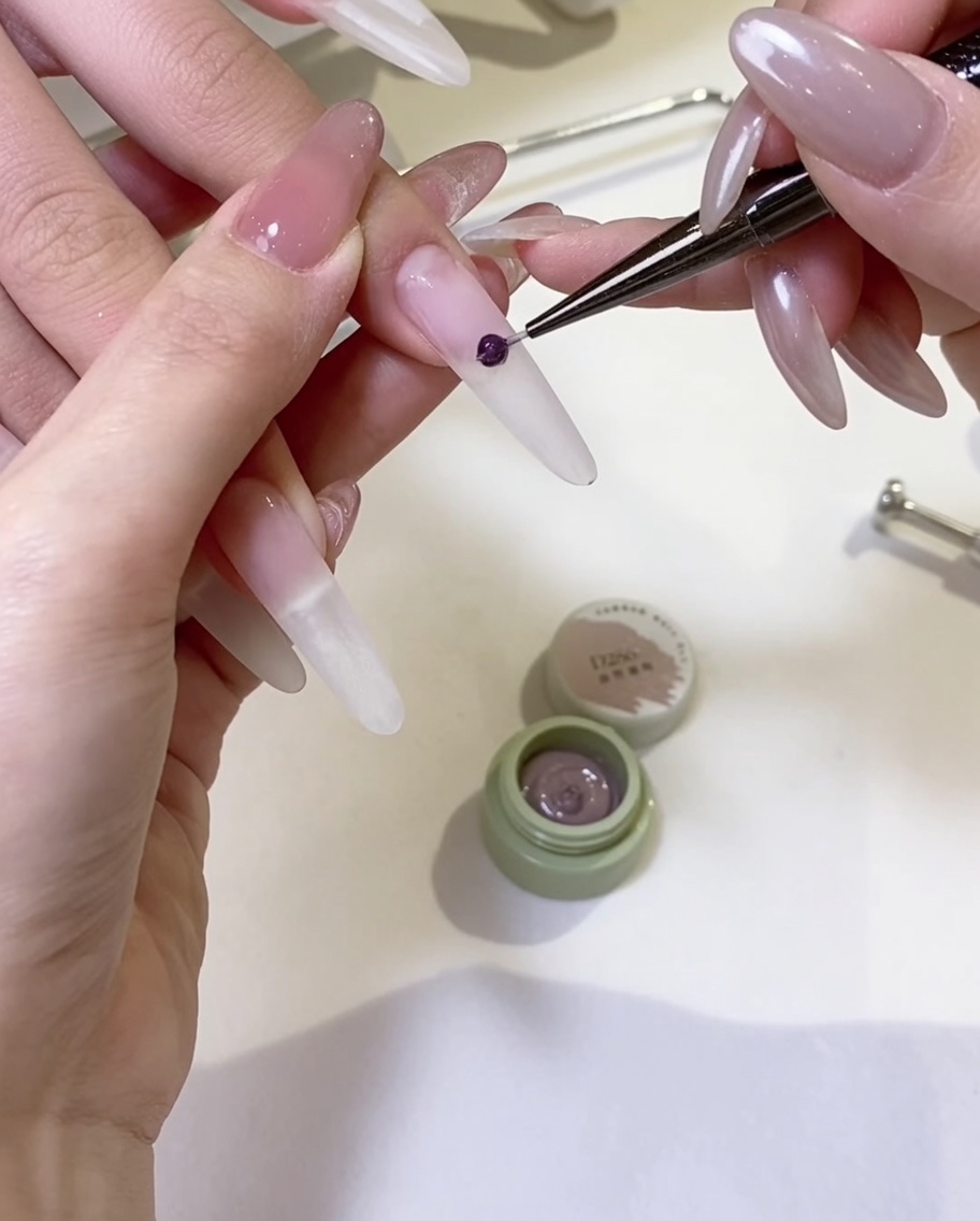 Un pinceau à gel appliquant une couche uniforme de vernis gel nude sur la surface de longle.