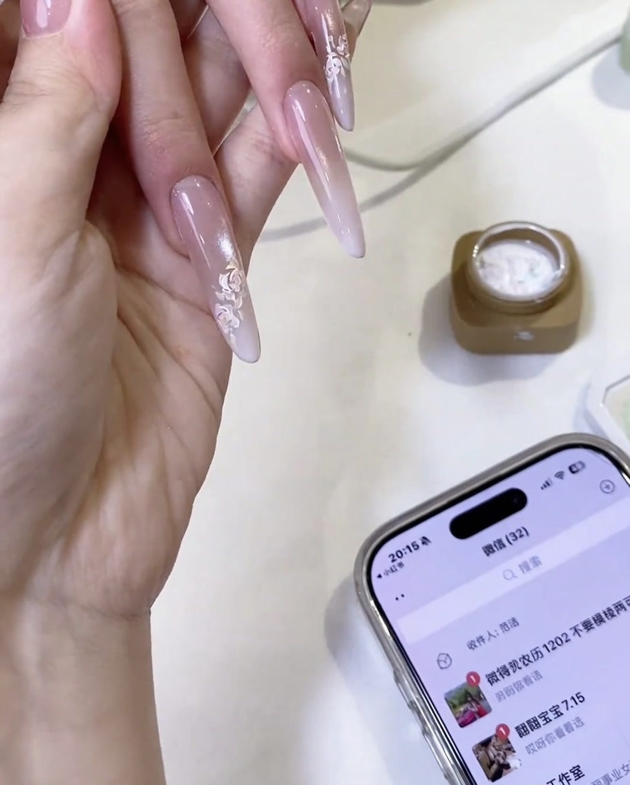 Une rose blanche peinte à la main terminée sur un ongle, avec des détails de pétales superposés.