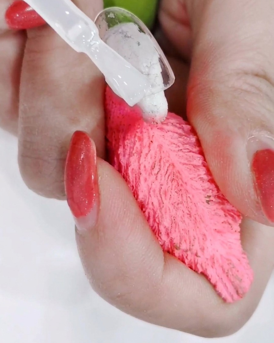 Une main positionnée sous une lampe UV professionnelle avec la lumière catalysant le top coat fraîchement appliqué.