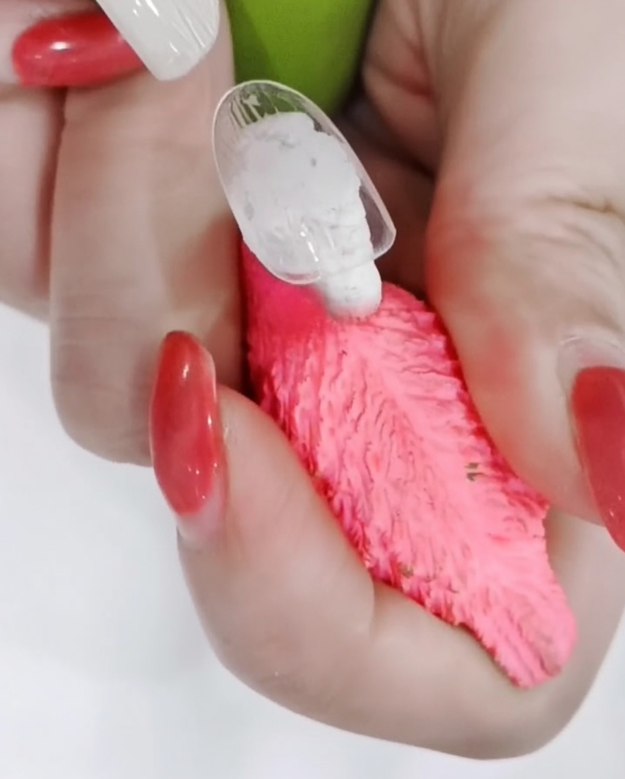 Gros plan montrant un pinceau fin traçant soigneusement les bords des pétales de marguerite blancs sur un ongle mat.