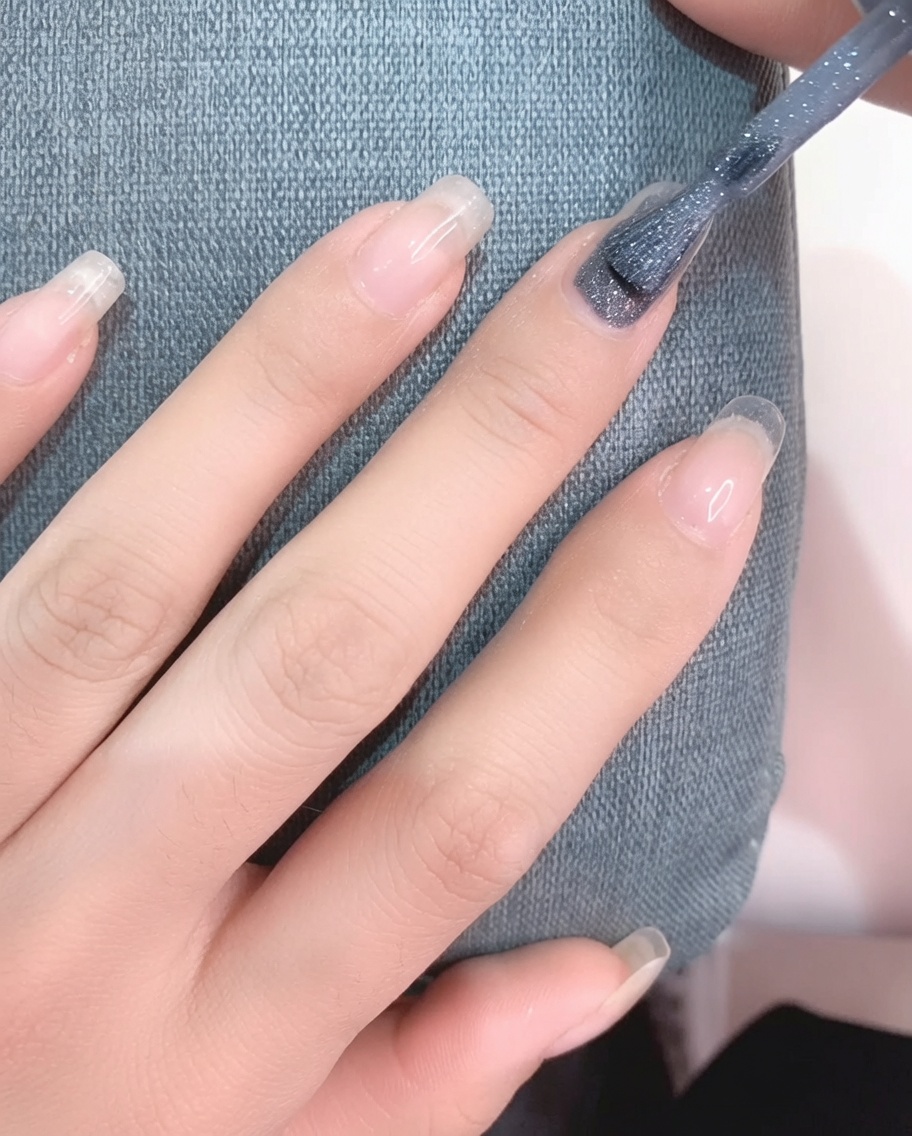 Vue en gros plan dun pinceau appliquant du vernis gel gris clair sur un ongle propre.